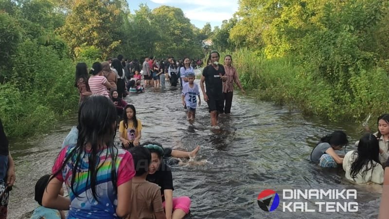 Anak-anak dan orang dewasa bermain air di jalan yang tergenang banjir di Buntok, Barito Selatan